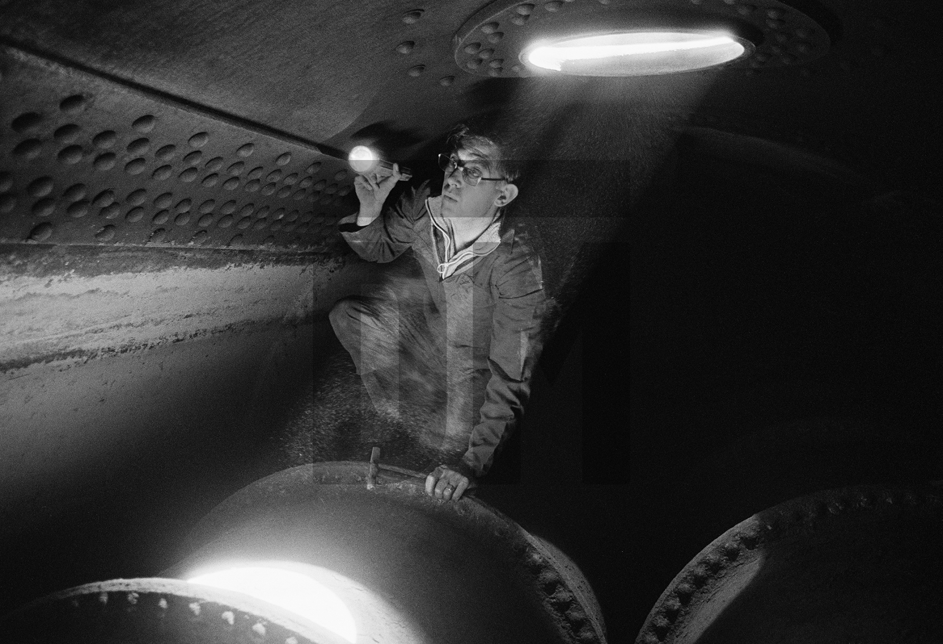 Insurance company boiler inspector on top of one of the furnace tubes inside the Lancashire boiler. Wakes holiday, July 1977 by Daniel Meadows