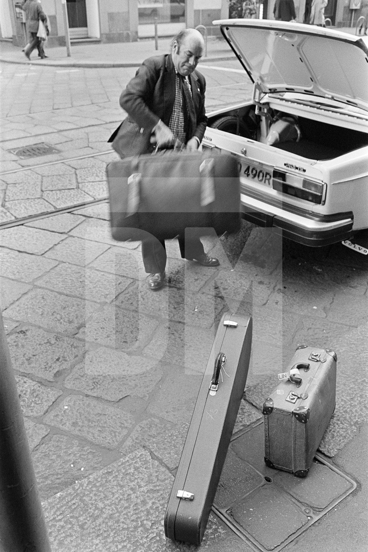 Julian Bream arriving at hotel and unpacking his car, Italy. March 1981 by Daniel Meadows