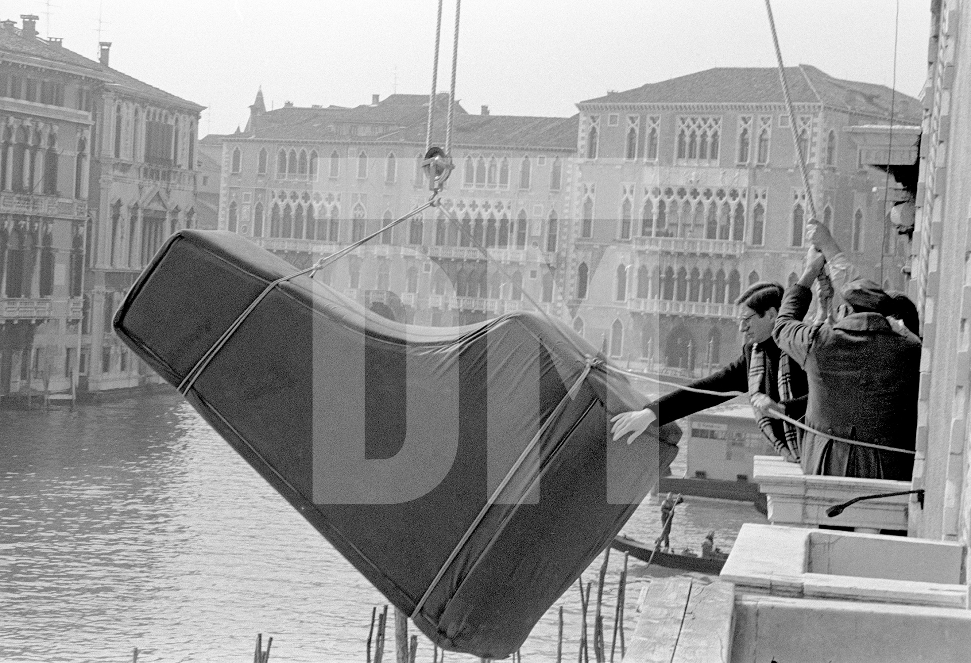 Tony Palmer [director] steadies a piano above the Grand Canal during filming of 'Wagner'. Venice 1982 by Daniel Meadows