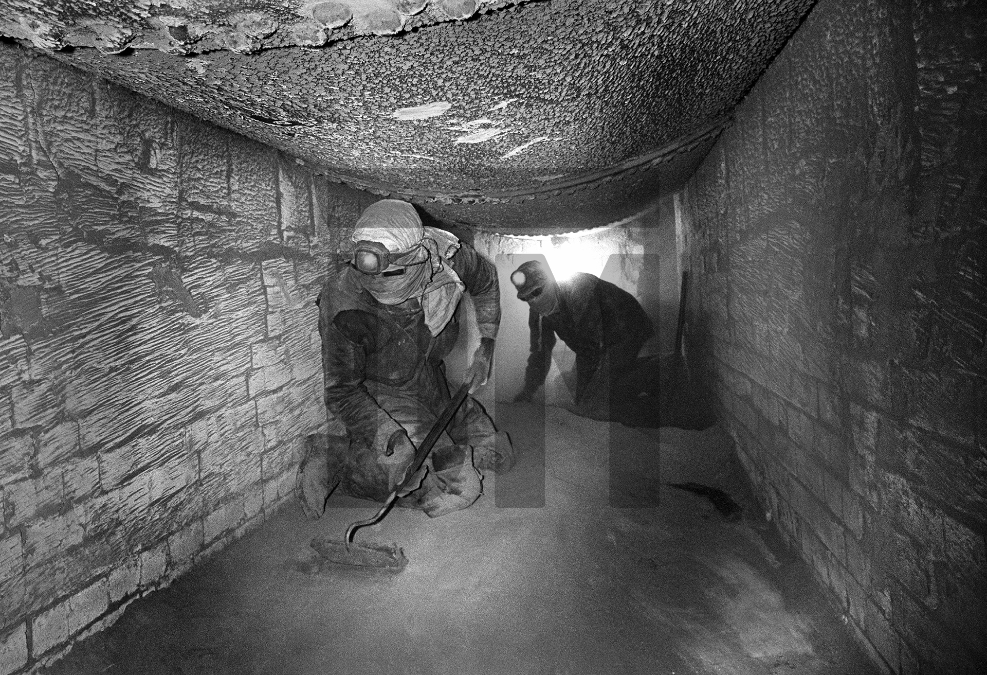 Working in the sole flue beneath the Lancashire boiler, raking fluedust. Easter holiday, April 1976 by Daniel Meadows