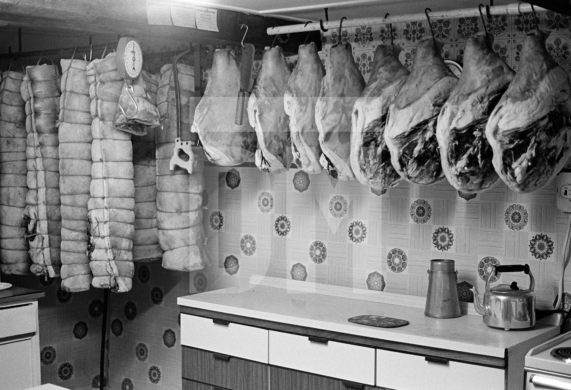 Rolls of bacon and hams hang in the farmhouse kitchen. North Yorkshire 1976 by Daniel Meadows