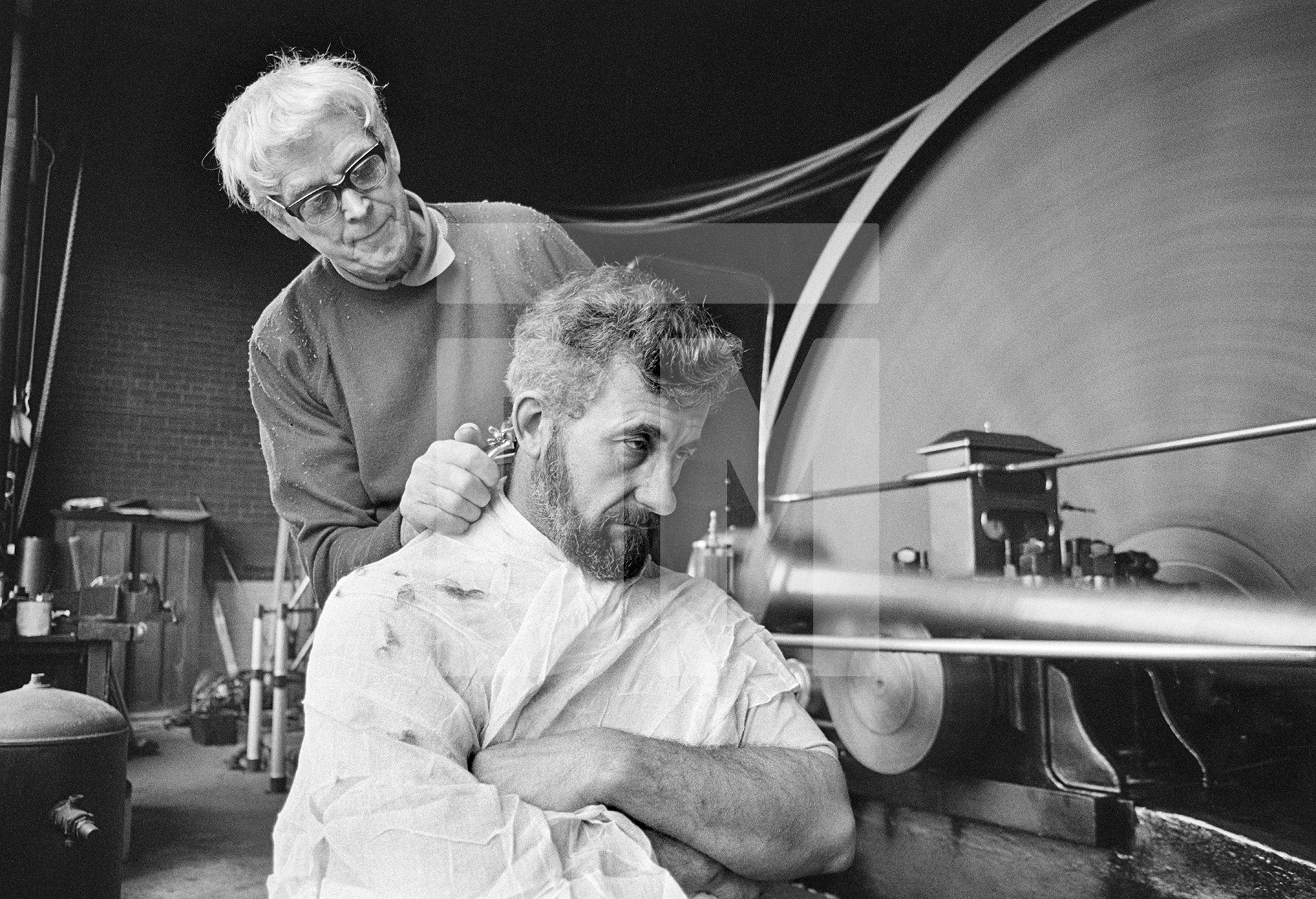 In the engine house. Stanley Graham, mill engineer, having his hair cut. March 1977 by Daniel Meadows