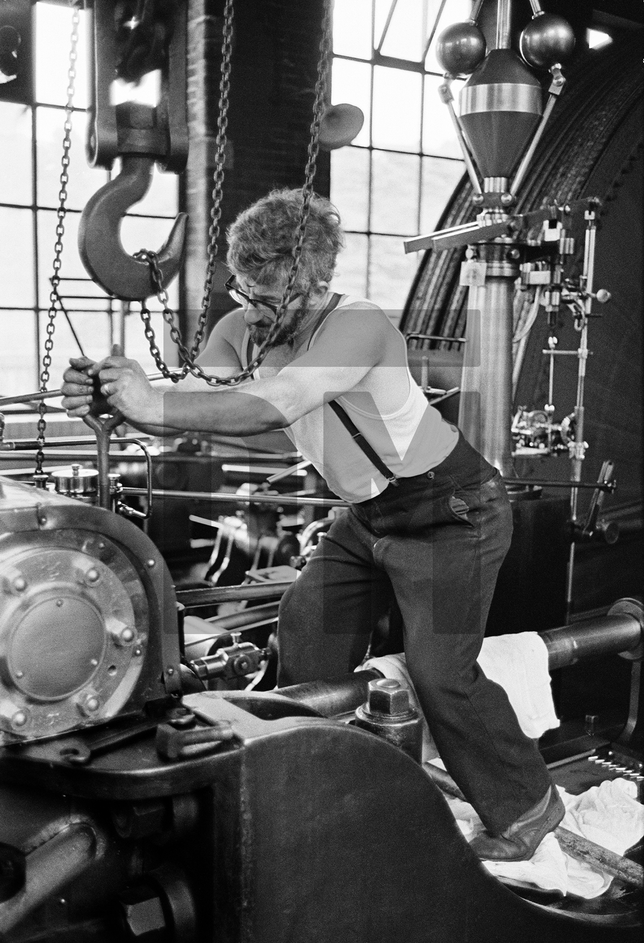 In the engine house. Stanley Graham, mill engineer. Maintenance, repairs to gland packing on high pressure cylinder. June 1976 by Daniel Meadows