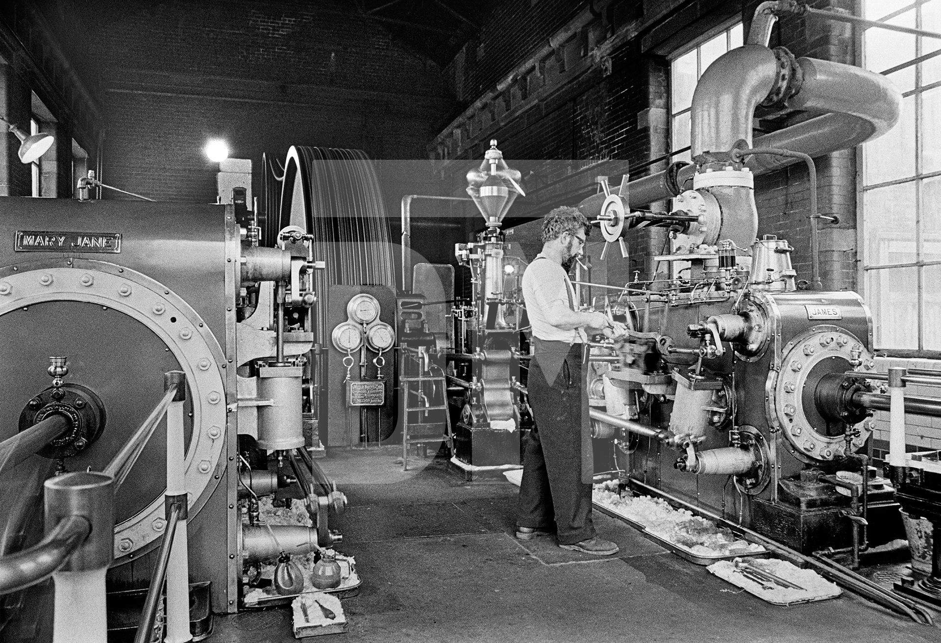 In the engine house with Stanley Graham, mill engineer. Double acting cross compound condensing engine, made by William Roberts & Sons of Nelson, commissioned 1919. Photographed 1976 by Daniel Meadows