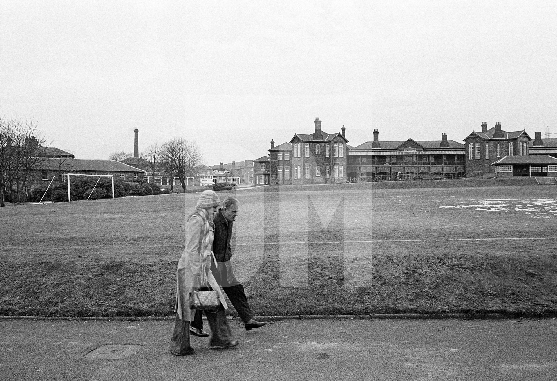 Staff and patients participate in a behaviour modification token economy scheme. Here George Quann, aged 52 a former labourer who was admitted in 1952, is accompanied on a walk in the hospital grounds. February 1978 by Daniel Meadows