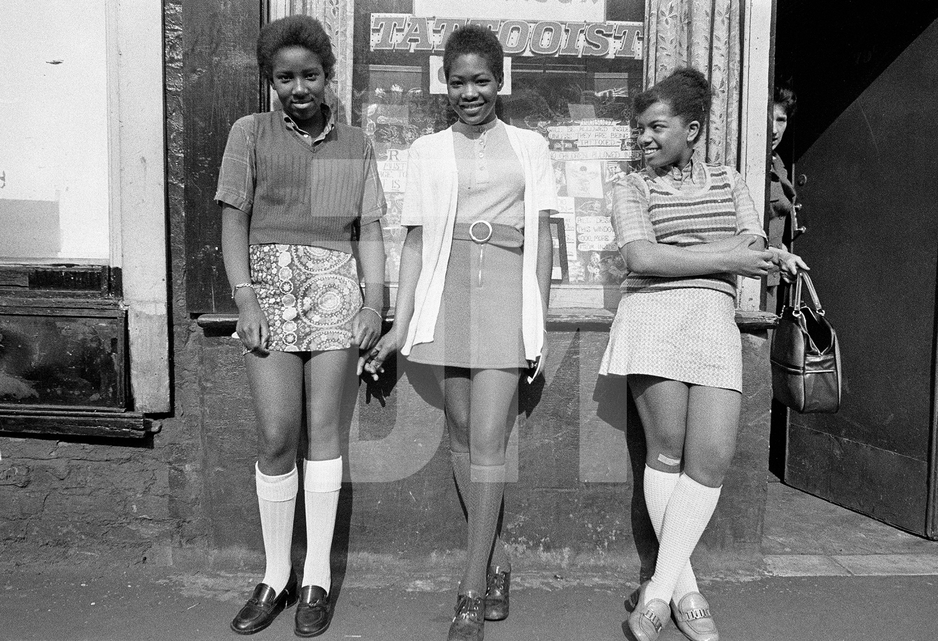 Left Joanne McKenzie, middle Donna Duncan. Teenagers outside the tattoo parlour at no.79C Greame Street, adjacent to The Shop on Greame Street, Moss Side, Manchester. 1972 by Daniel Meadows