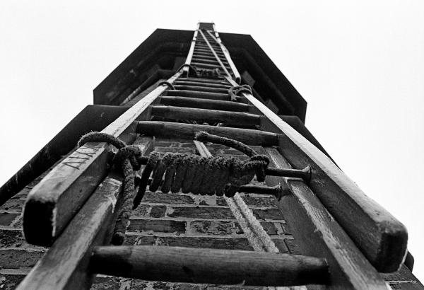 Looking up at the oversailer from just beneath the lower string course. Ladders are all in place with lashings clearly visible. September 1976