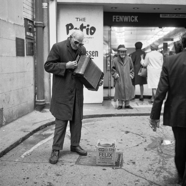 Blind accordion player, busking outside deprtment store, Newcastle upon Tyne. September 1974