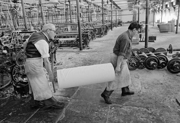 In the weaving shed, cloth carrier and weaver with loom-state cloth. May 1976