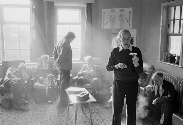 In the day-room, Stanley Massey aged 57 (foreground) rolls a cigarette, Clayton Ward, Prestwich Psychiatric Hospital, Manchester. February 1978
