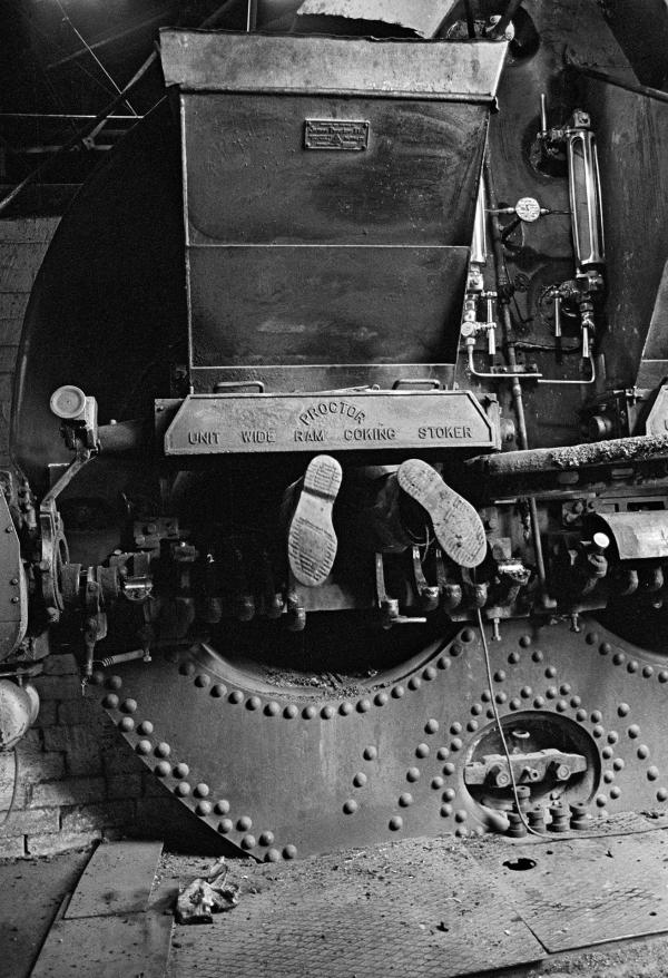 Only the feet of engineer Stanley Graham can be seen as he works on the fire bars in the Lancashire boiler. Wakes holiday, July 1976