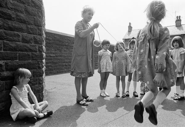 Dinner lady, with children skipping, Church of England County Primary School, Barrowford, Lancashire. August 1976