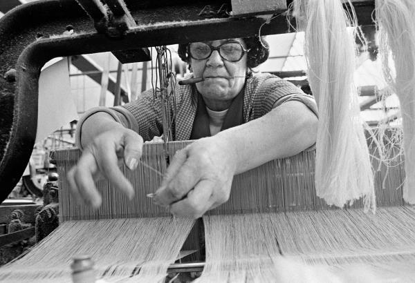 A weaver works at a loom in her alley, ‘taking up an end’. May 1976