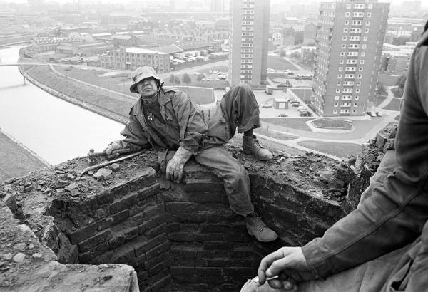 150 feet up, atop of the stack and shortly after starting the demolition process, Peter Tatham steeplejack poses for his portrait. September 1976