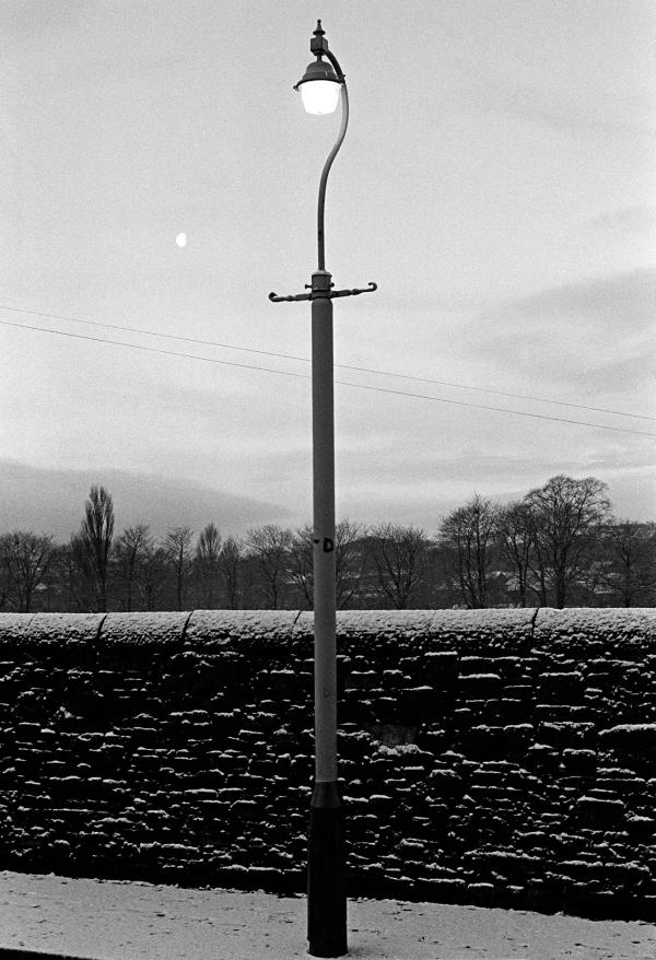 Street lamp, moon and snow, twilight, Nelson, Lancashire. January 1977