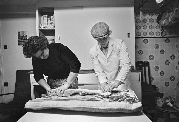 Elsie Richardson and Tony Critchley begin to roll a flitch of bacon. North Yorkshire 1976