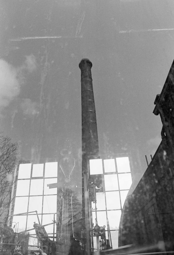 The chimney reflected in a window of the engine house. April 1976