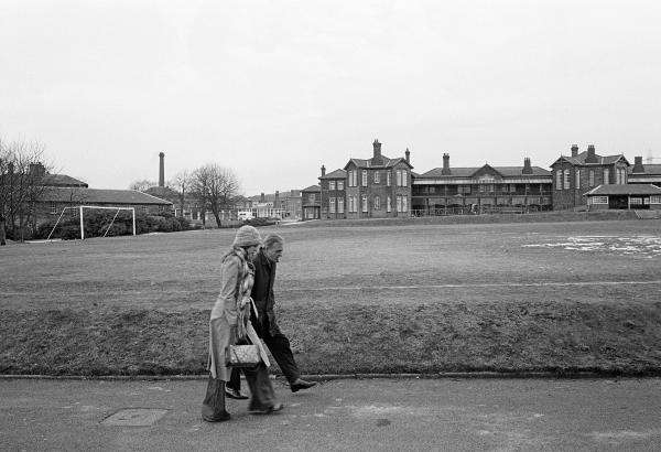Staff and patients participate in a behaviour modification token economy scheme. Here George Quann, aged 52 a former labourer who was admitted in 1952, is accompanied on a walk in the hospital grounds. February 1978