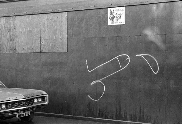 WMD (weapons of mass destruction) registration plate on American car, guard dog warning sign and white graffiti penis, Hull. November, 1981